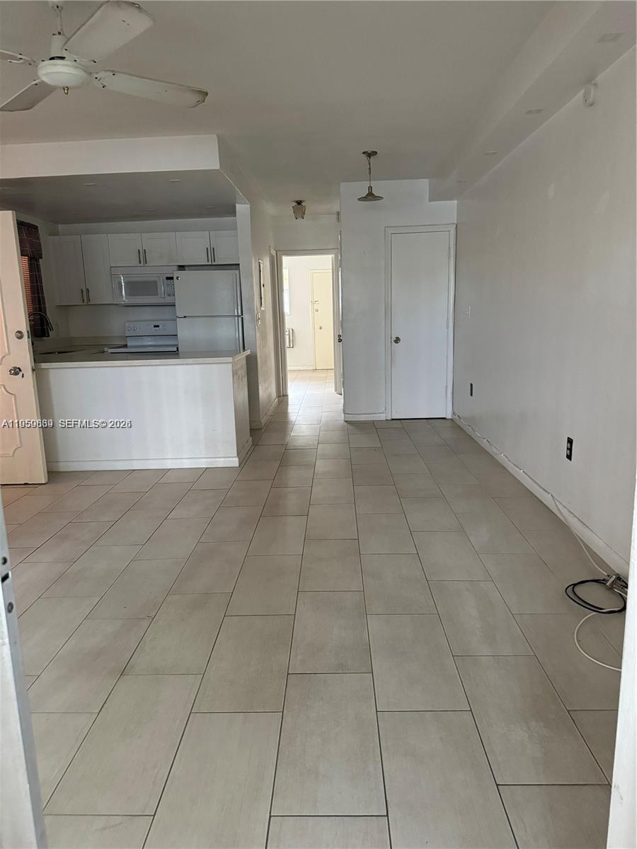 This room features white cabinets, a kitchen island, and light-colored tile flooring throughout — 285 NE 191st St # 2907, Miami FL 33179, MIAMI, FL