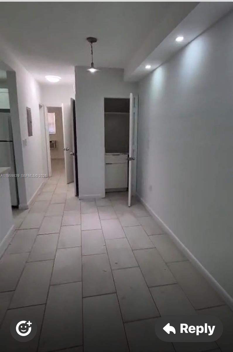 A hallway with light-colored tile flooring leads to an open doorway and a closet — 285 NE 191st St # 2907, Miami FL 33179, MIAMI, FL
