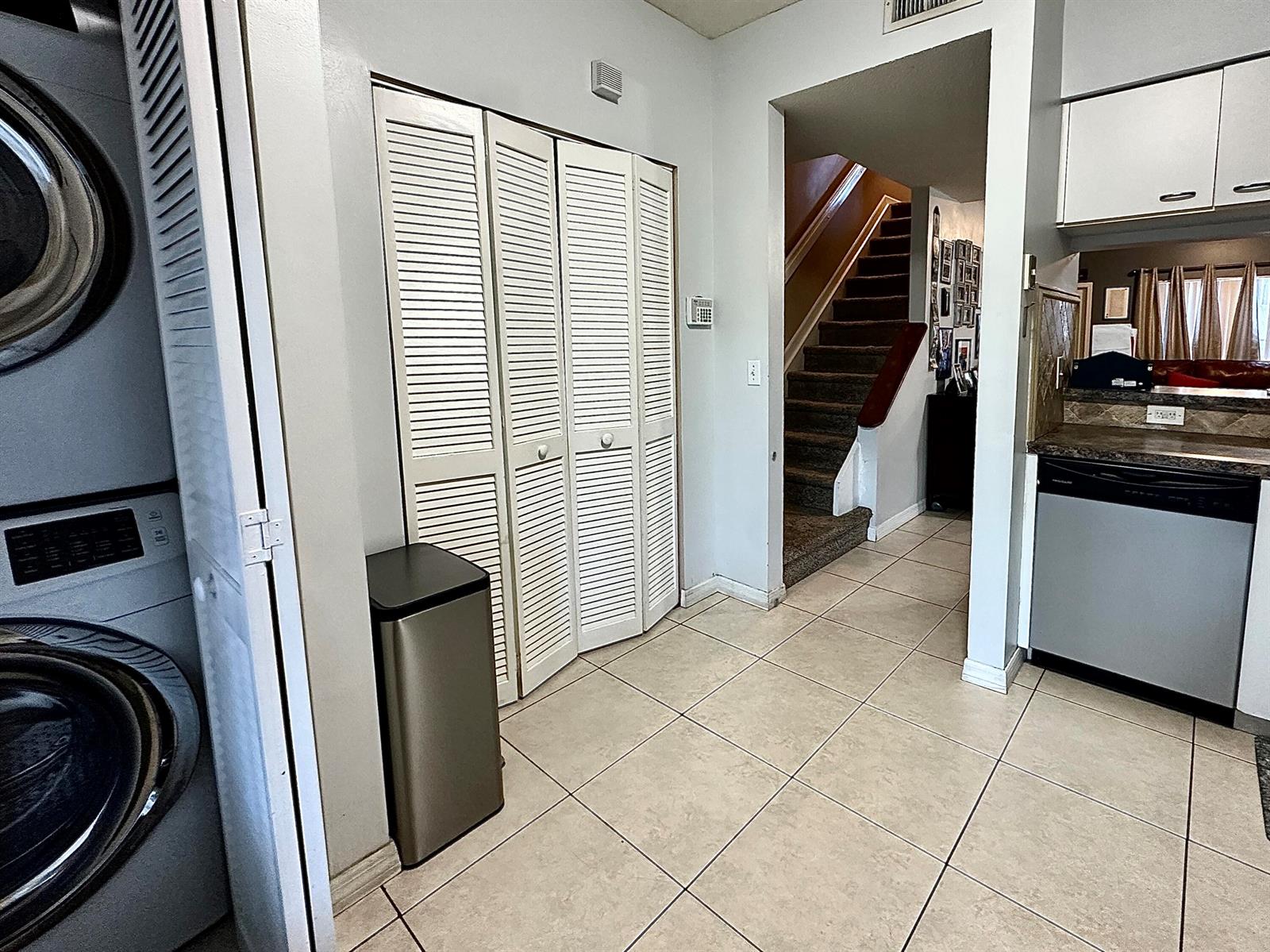 A tiled laundry area features a stacked washer-dryer, louvered closet doors, and a nearby staircase — 5336 Jubilee Way # 189, Margate FL 33063, MARGATE, FL