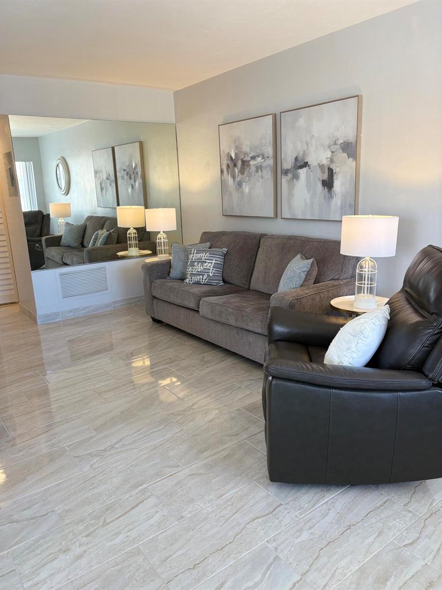 A living room features a gray sofa, a dark leather recliner, and light tile flooring — 3280 Lake Osborne Drive # 206, FL 33461, FL