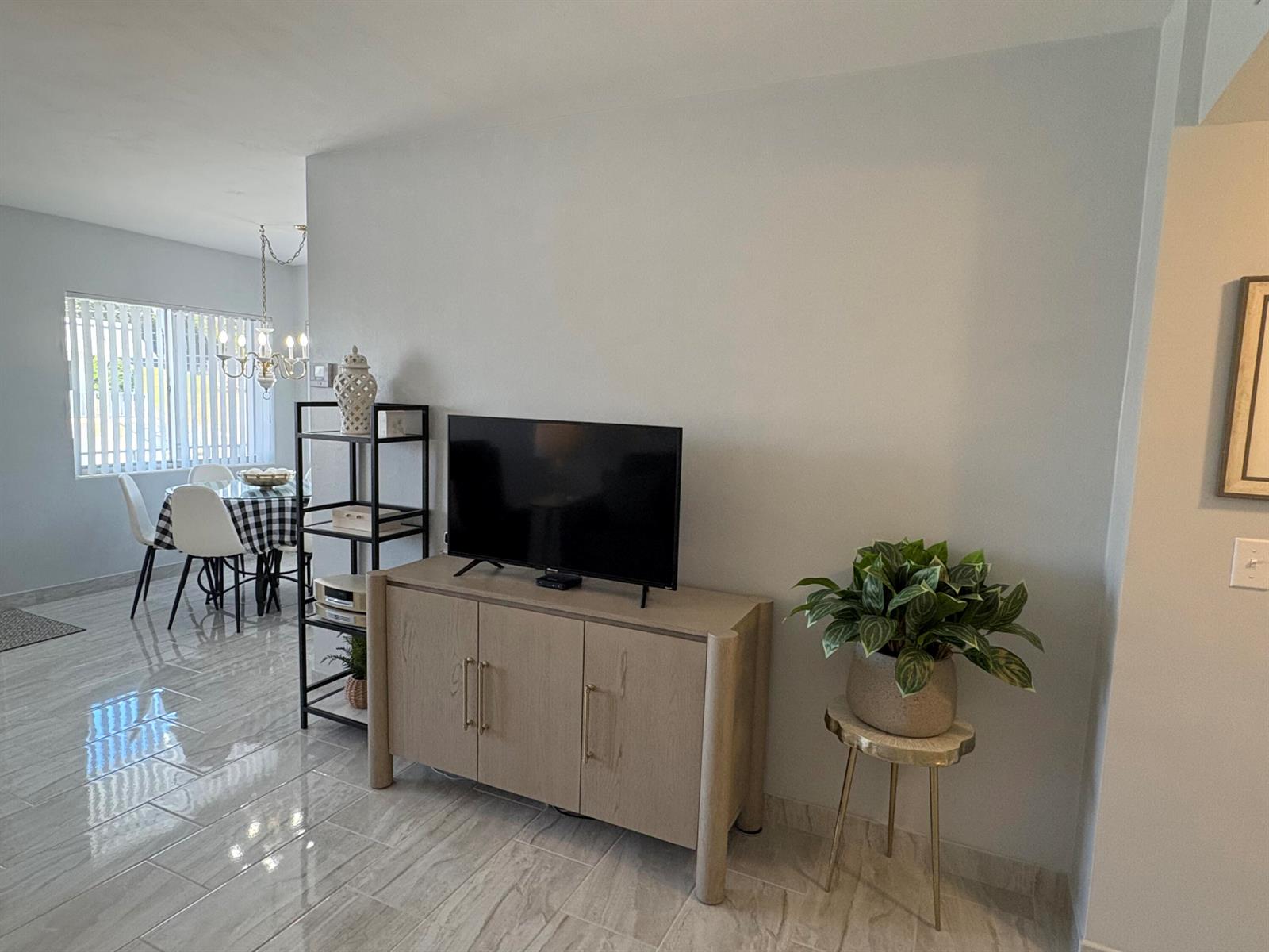 A living room features a television on a wooden cabinet, a metal shelving unit, and a plant — 3280 Lake Osborne Drive # 206, FL 33461, FL