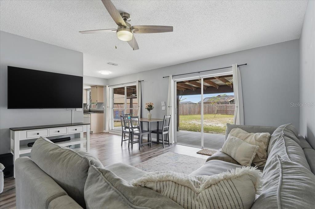 A living room with a gray sectional, dining area, and sliding doors leading to a patio — 8913 WOOD LAKE COURT, NEW PORT RICHEY, FL