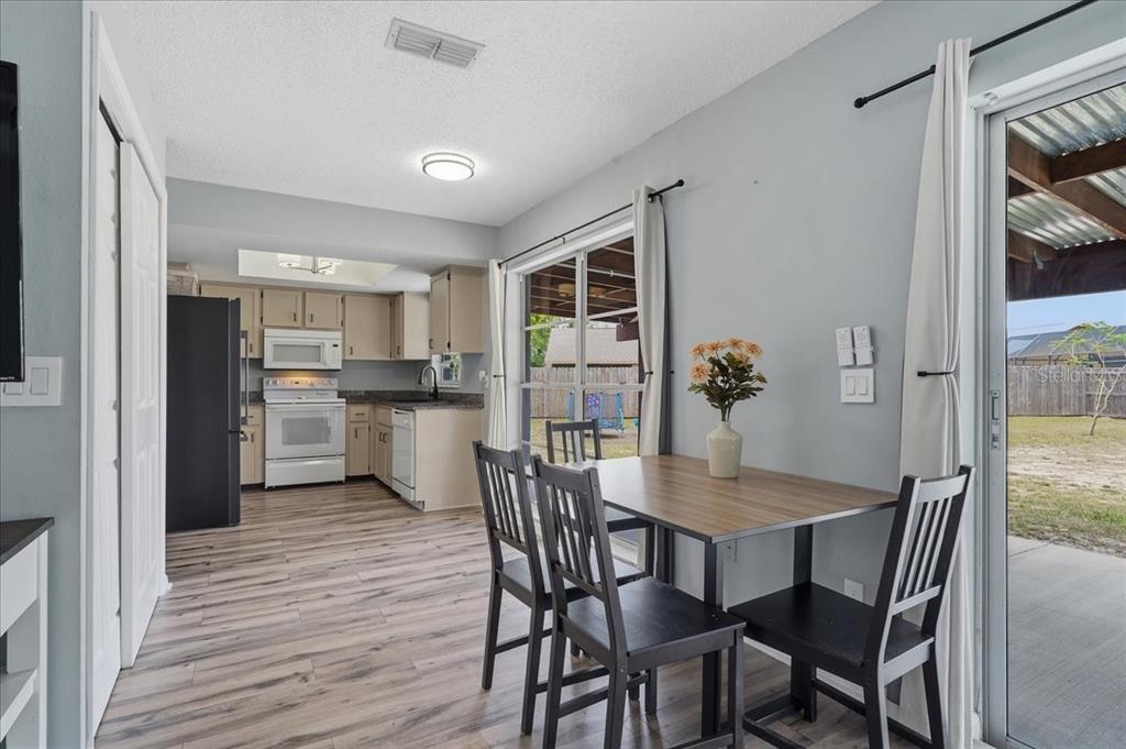 A dining area with a table and chairs opens to a kitchen and a backyard — 8913 WOOD LAKE COURT, NEW PORT RICHEY, FL