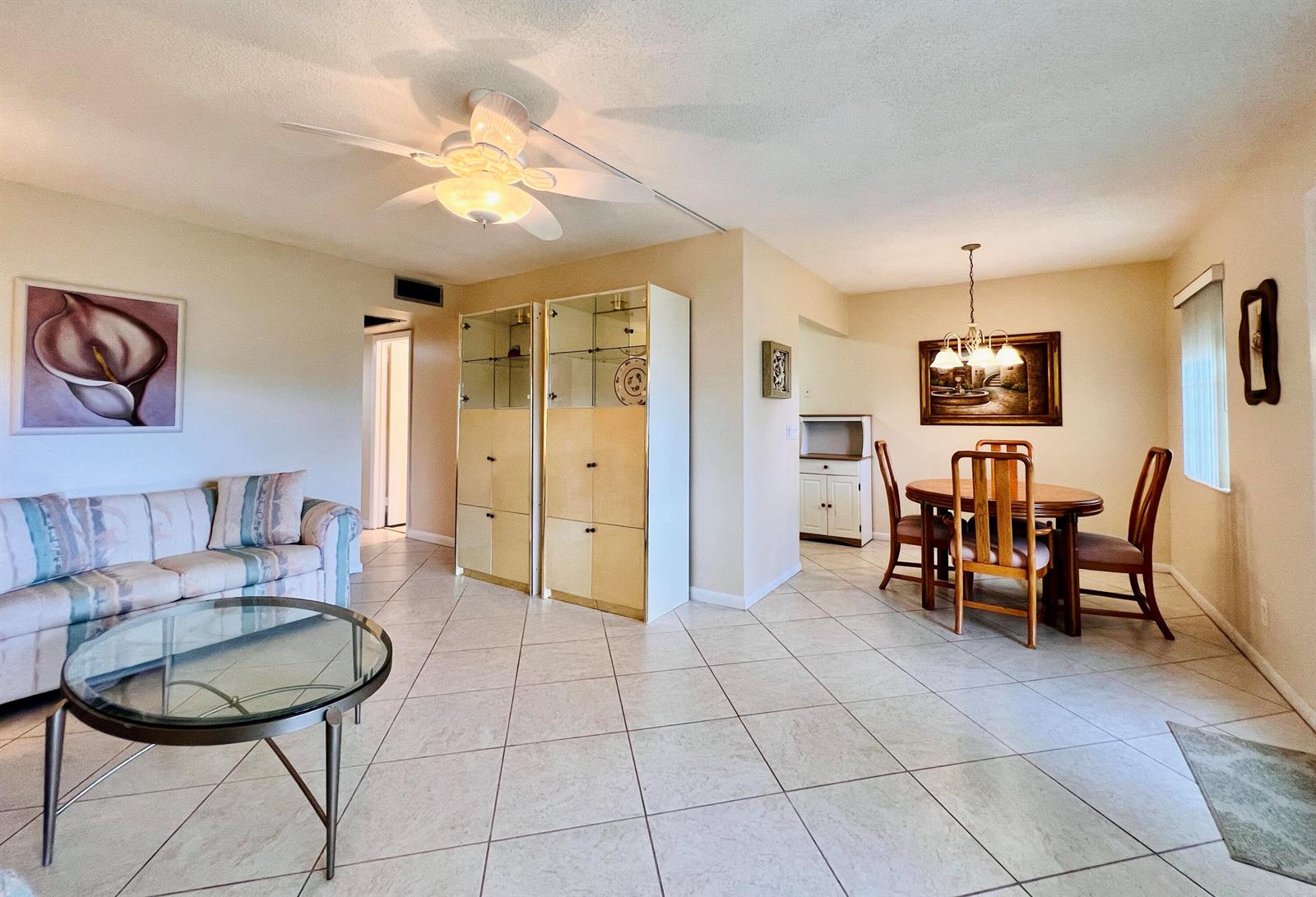 A living and dining area features tile flooring, a ceiling fan, and a glass coffee table — 27 Sheffield B, West Palm Beach FL 33417, WEST PALM BEACH, FL
