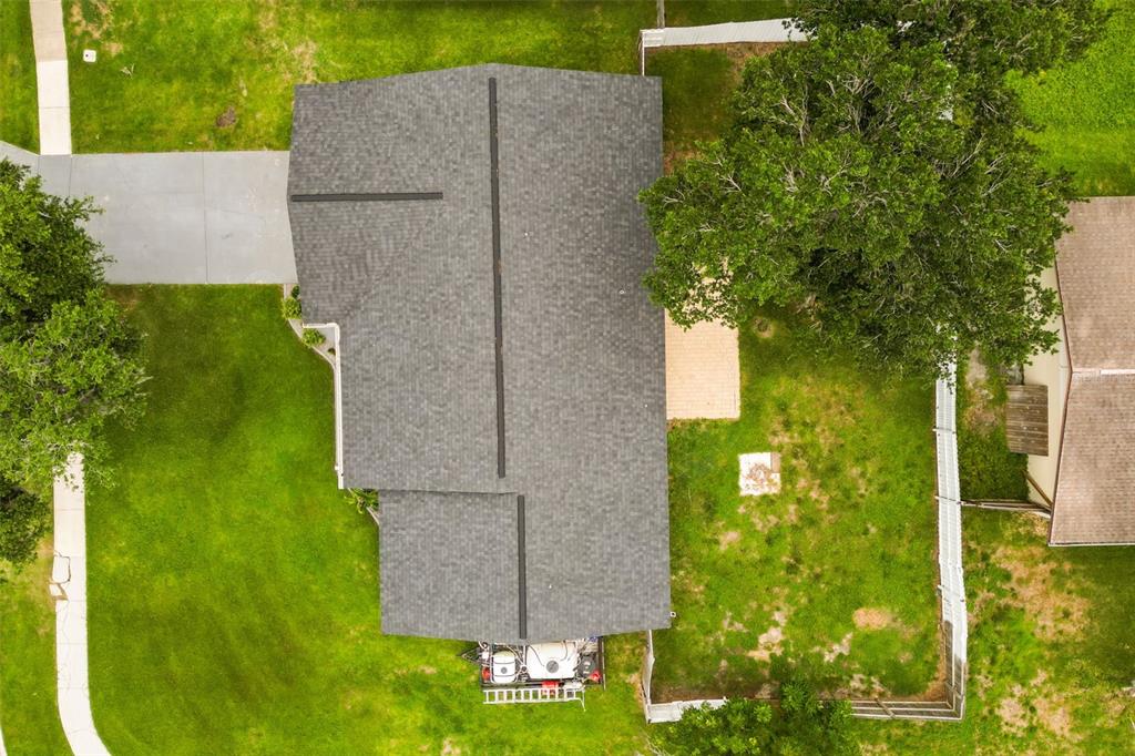 An aerial view shows a house with a gray shingled roof, a backyard, and trees — 5780 DEVON STREET, PORT ORANGE, FL