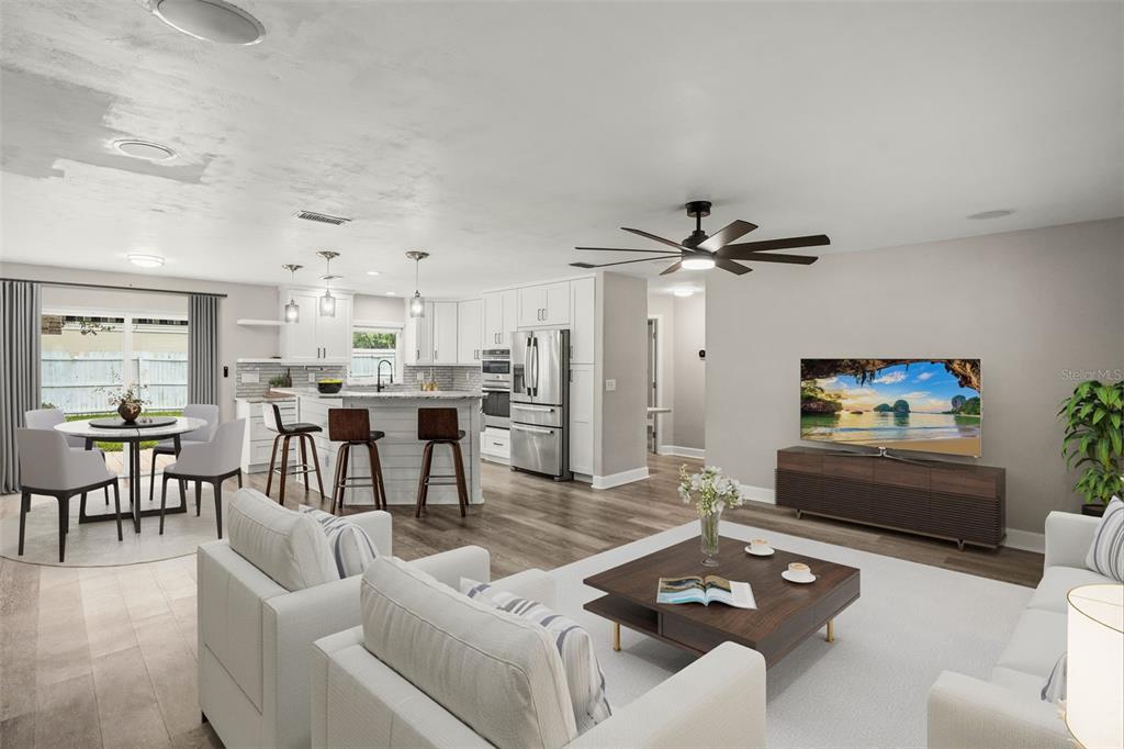 An open-concept living room and kitchen featuring white cabinetry, a breakfast bar, and wood flooring — 5780 DEVON STREET, PORT ORANGE, FL