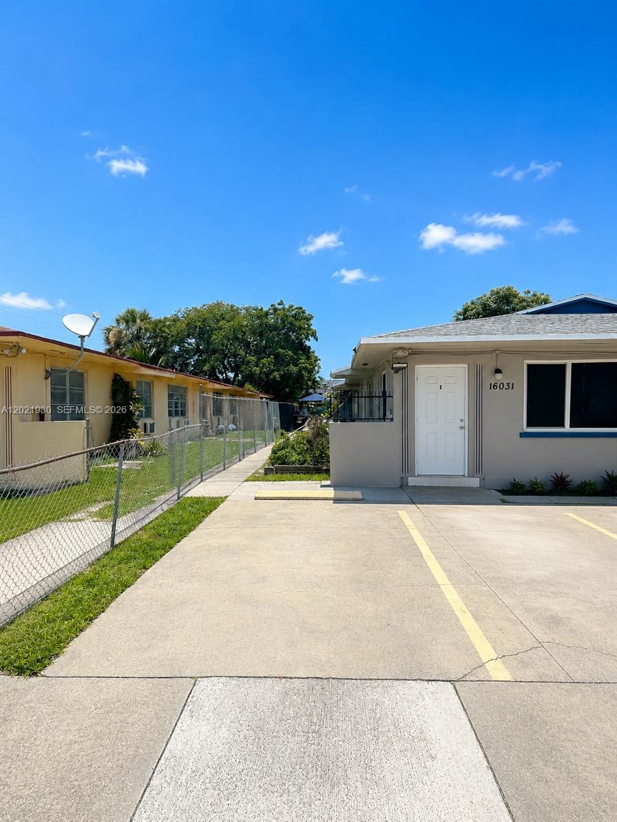 A concrete driveway leads to the entrance of a single-story building with a white door — 16031 NE 19th Pl, North Miami Beach FL 33162, NORTH MIAMI BEACH, FL