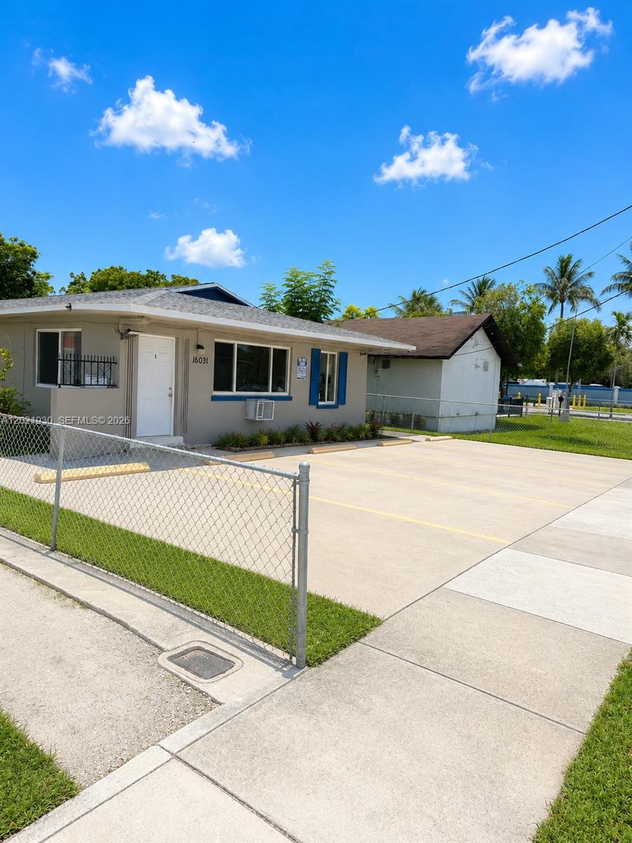 A single-story building with a gray exterior, blue shutters, and a paved parking lot — 16031 NE 19th Pl, North Miami Beach FL 33162, NORTH MIAMI BEACH, FL