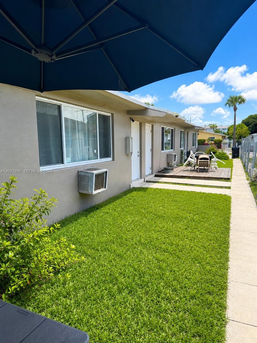 The exterior view shows a single-story building with a small lawn and wooden deck — 16031 NE 19th Pl, North Miami Beach FL 33162, NORTH MIAMI BEACH, FL