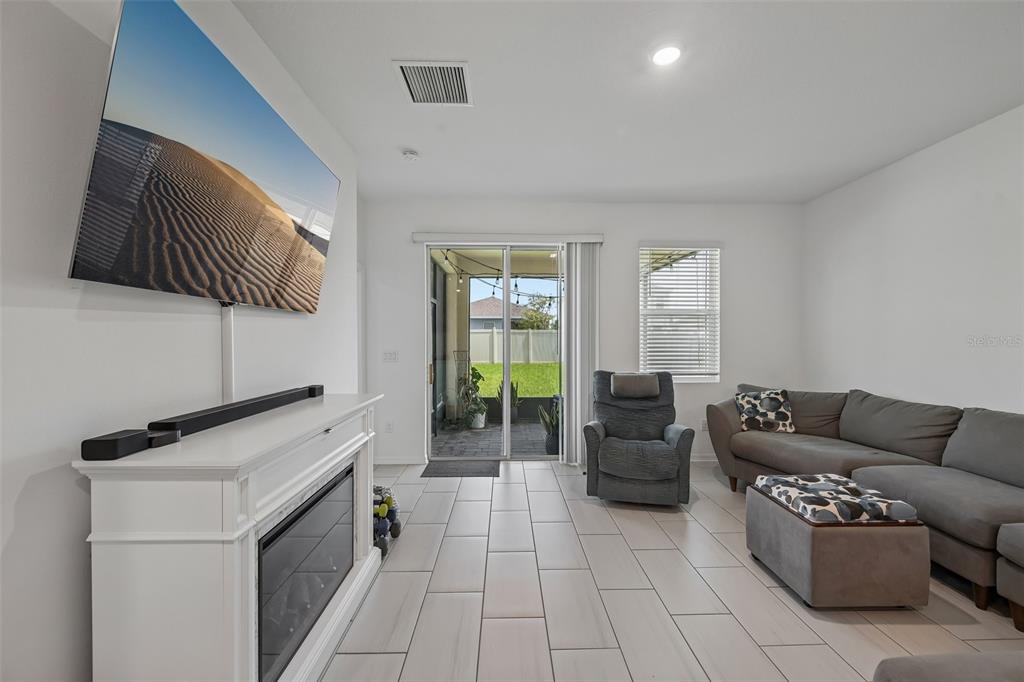 A living room features a white fireplace, a wall-mounted television, tile flooring, and a sliding door — 5518 LOS ROBLES COURT, PALMETTO, FL