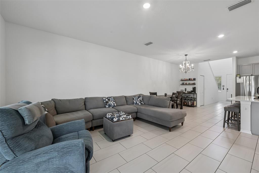 A living room with a large gray sectional sofa, a matching ottoman, and tile flooring — 5518 LOS ROBLES COURT, PALMETTO, FL