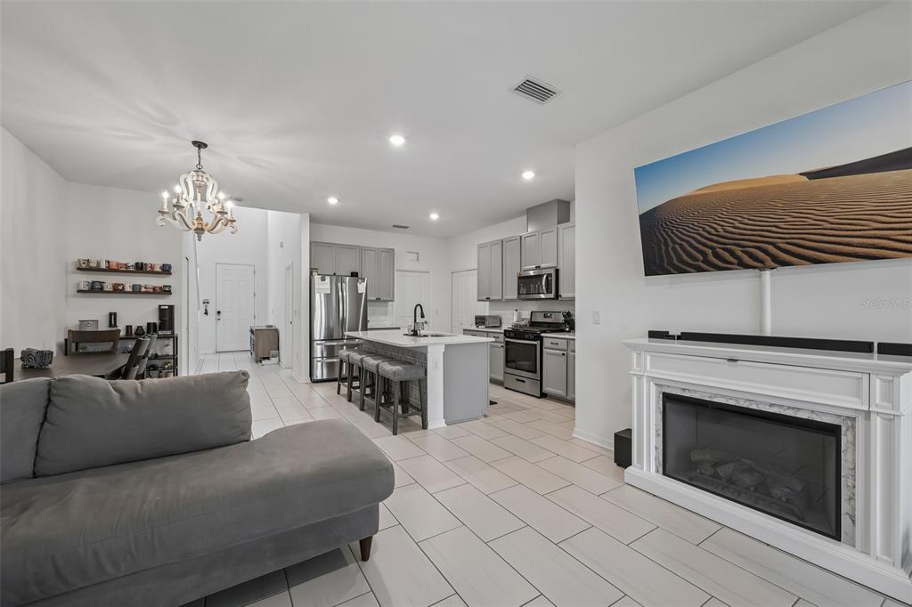 An open-concept living room and kitchen featuring a grey sofa, fireplace, and kitchen island — 5518 LOS ROBLES COURT, PALMETTO, FL
