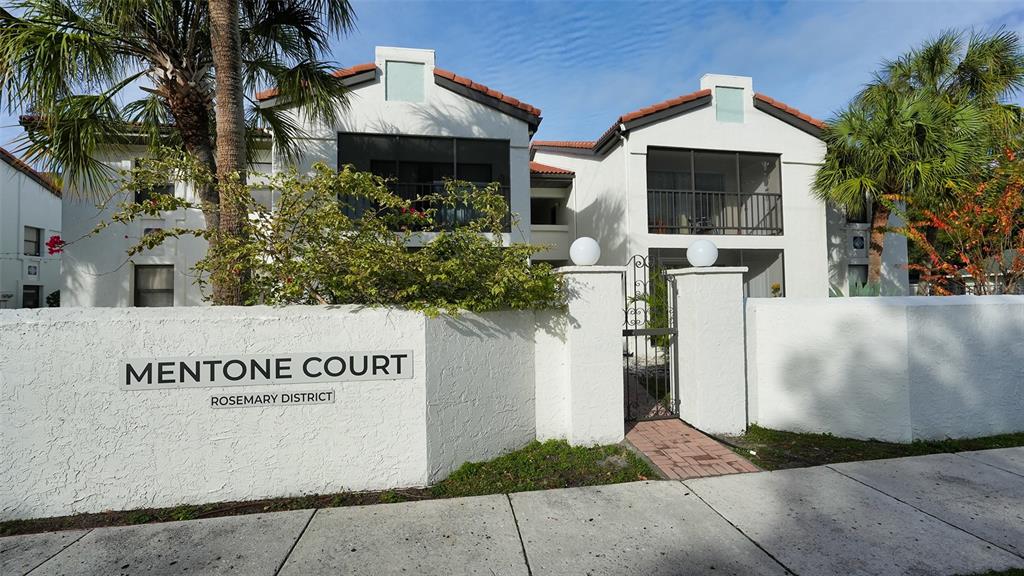 The exterior of a white stucco apartment building features a gated entrance and palm trees — 631 N ORANGE AVENUE UNIT 107, SARASOTA, FL