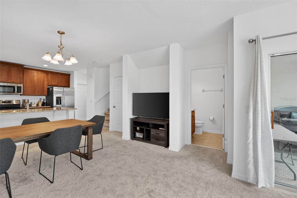 A dining area with a wooden table and chairs sits adjacent to a kitchen and living space — 1188 WOODY CYPRESS DRIVE, KISSIMMEE, FL