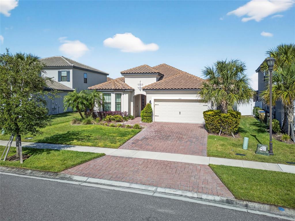 A single-story house with a tiled roof, brick driveway, and palm trees in the front yard — 1910 GOBLET COVE STREET, KISSIMMEE, FL