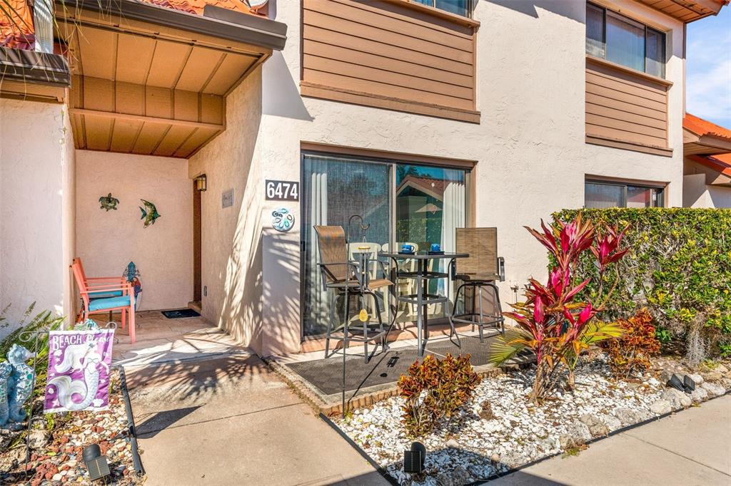 The exterior of a residential unit features a patio with outdoor furniture and landscaping — 6474 DRAW LANE UNIT 77, SARASOTA, FL
