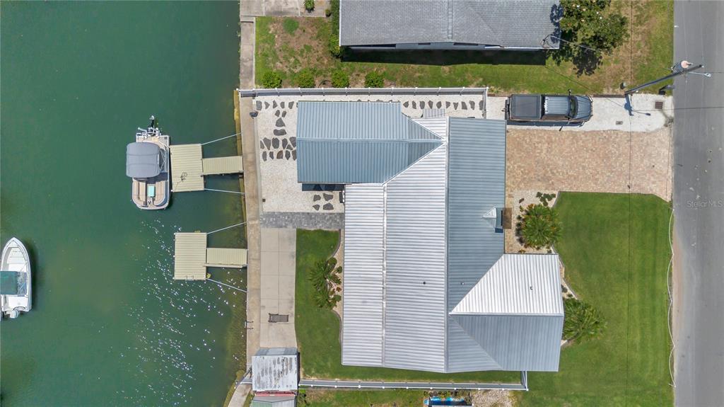 An aerial view shows a waterfront house with a metal roof, two boat docks, and a driveway — 1409 SE 4TH AVENUE, CRYSTAL RIVER, FL