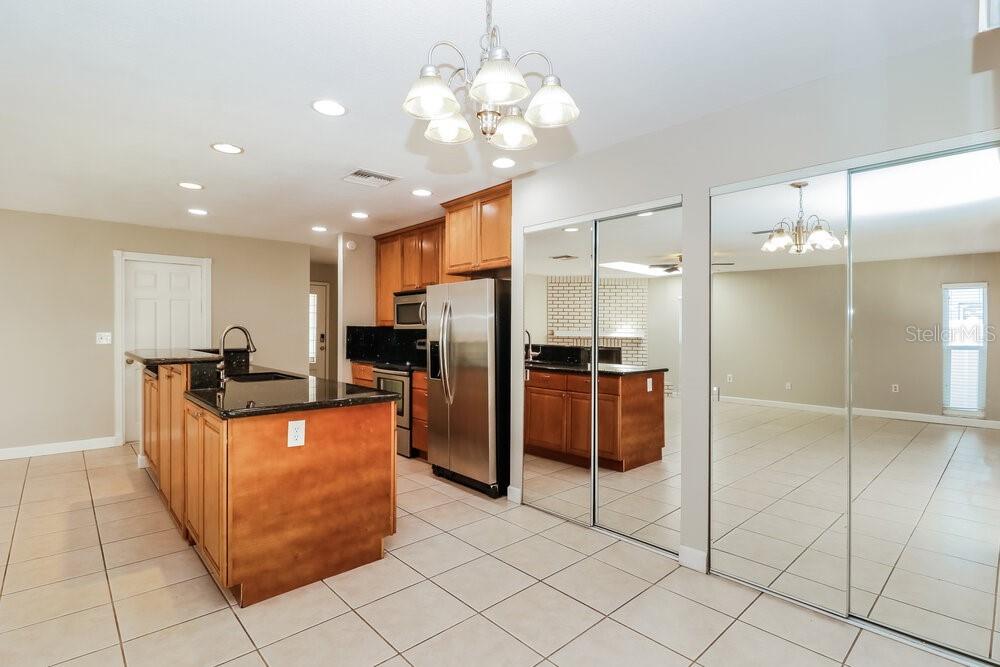 A kitchen with wood cabinets, granite countertops, a center island, and mirrored closet doors — 1701 E ORANGESIDE ROAD, PALM HARBOR, FL
