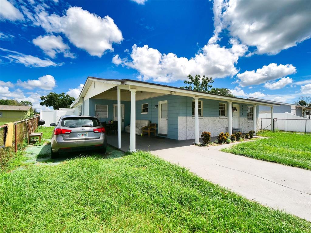 A single-story house with a blue exterior, a covered carport, and a parked silver car — 7018 GLENVIEW DRIVE, TAMPA, FL
