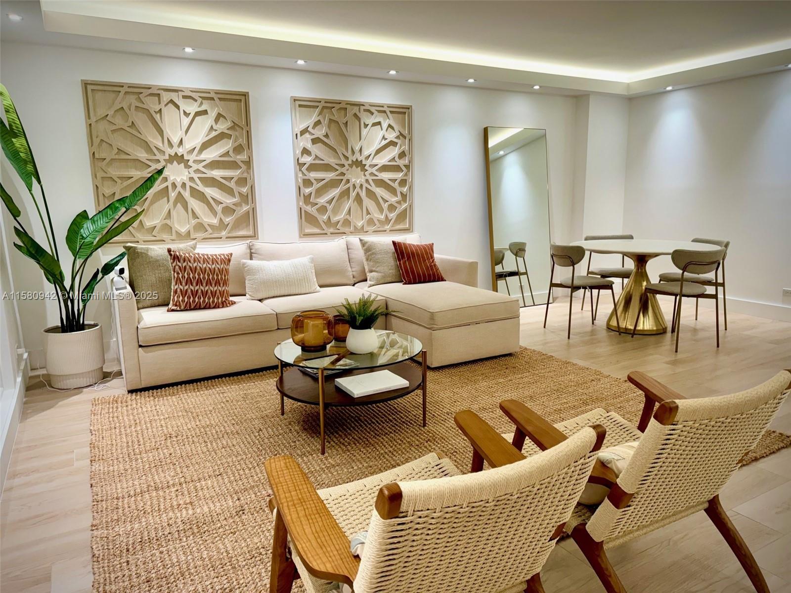A living room features a beige sectional sofa, two woven chairs, and geometric wall art — 2301 Collins Ave # 837, Miami Beach FL 33139, MIAMI BEACH, FL