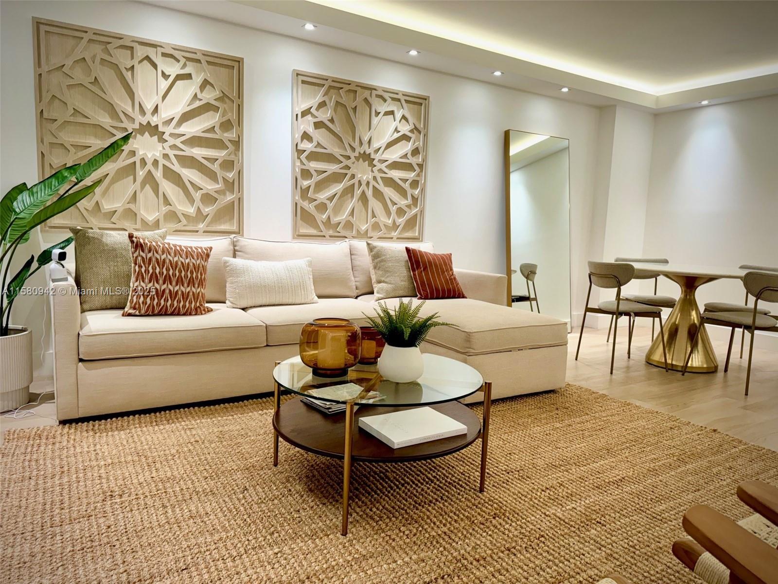 A living room features a beige sectional sofa, geometric wall art, and a round coffee table — 2301 Collins Ave # 837, Miami Beach FL 33139, MIAMI BEACH, FL