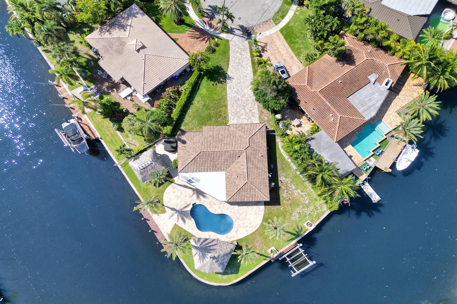 An aerial view shows a waterfront house with a pool, tiki huts, and boat docks — 271 SE 5th Terrace, Pompano Beach FL 33060, POMPANO BEACH, FL