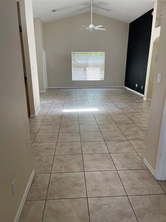 A spacious living room features light-colored tile flooring, a vaulted ceiling, and a black accent wall — 1908 BOBTAIL DR, MAITLAND, FL