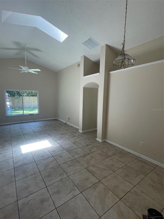 A living area with tile floors, a vaulted ceiling, a skylight, and a ceiling fan — 1908 BOBTAIL DR, MAITLAND, FL