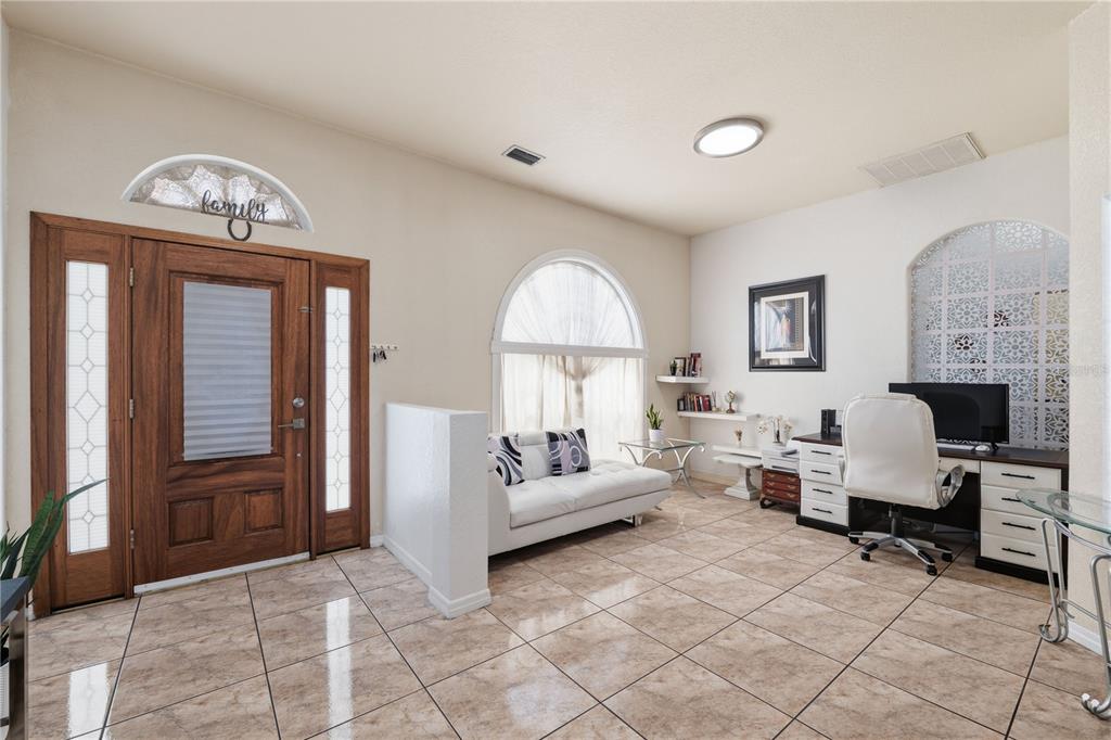 A bright entryway features tile flooring, a wooden front door, a sofa, and a desk — 1907 W MOHAWK AVENUE, TAMPA, FL