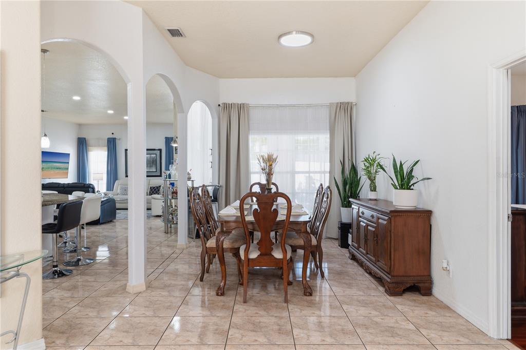 A dining room features a wooden table, chairs, a sideboard, and tile flooring — 1907 W MOHAWK AVENUE, TAMPA, FL