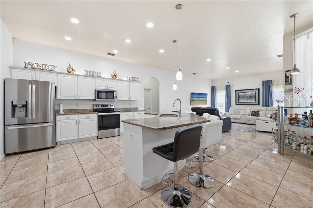 A kitchen with white cabinets, granite countertops, and a center island with bar stools — 1907 W MOHAWK AVENUE, TAMPA, FL