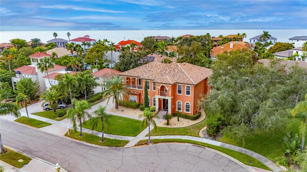 An aerial view shows a two-story orange stucco house with a tiled roof near water — 5910 LA ROSA LANE, APOLLO BEACH, FL