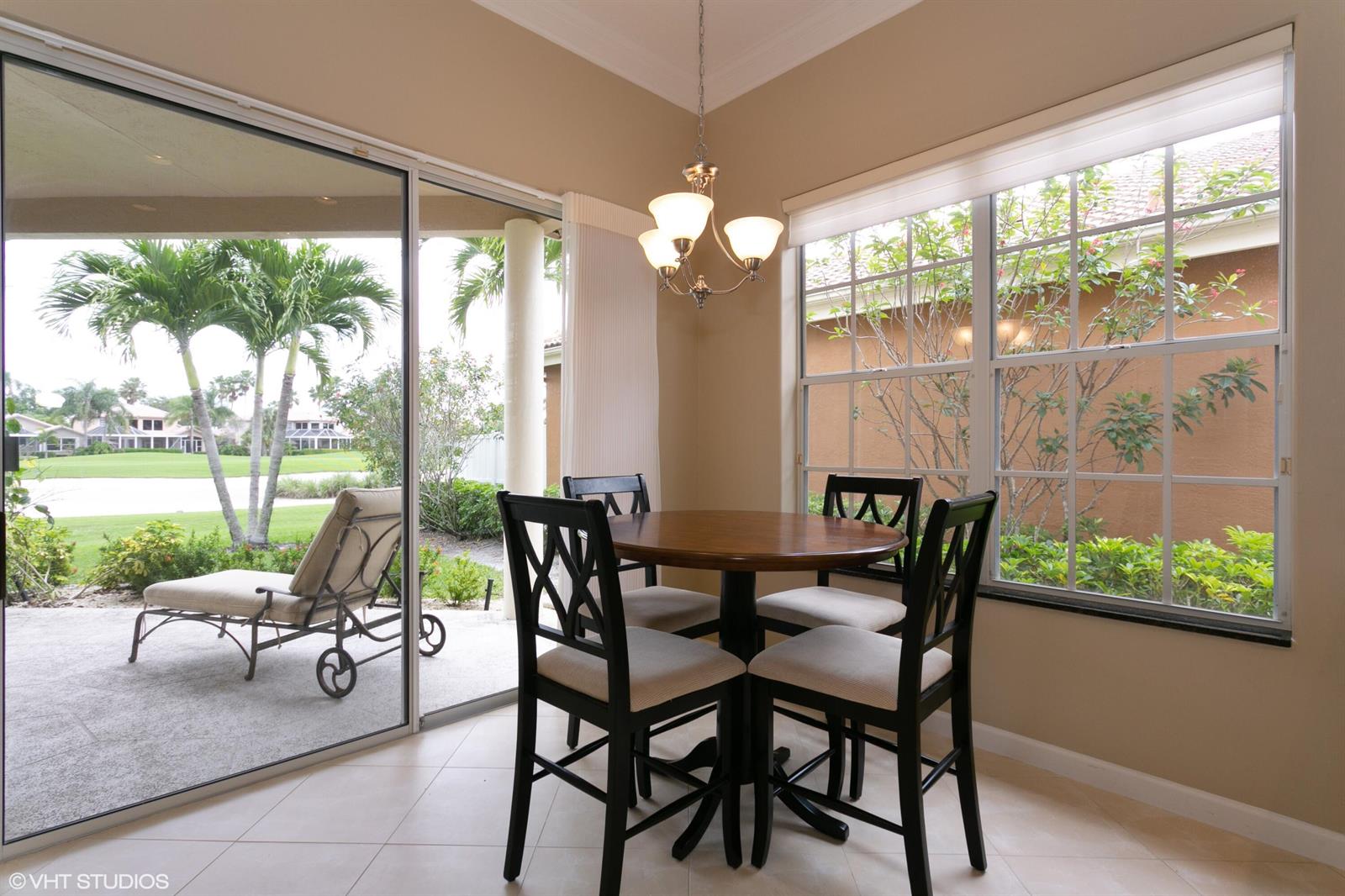 A dining nook features a round wooden table, four chairs, and a sliding glass door — 8407 Quail Meadow Way, West Palm Beach FL 33412, WEST PALM BEACH, FL