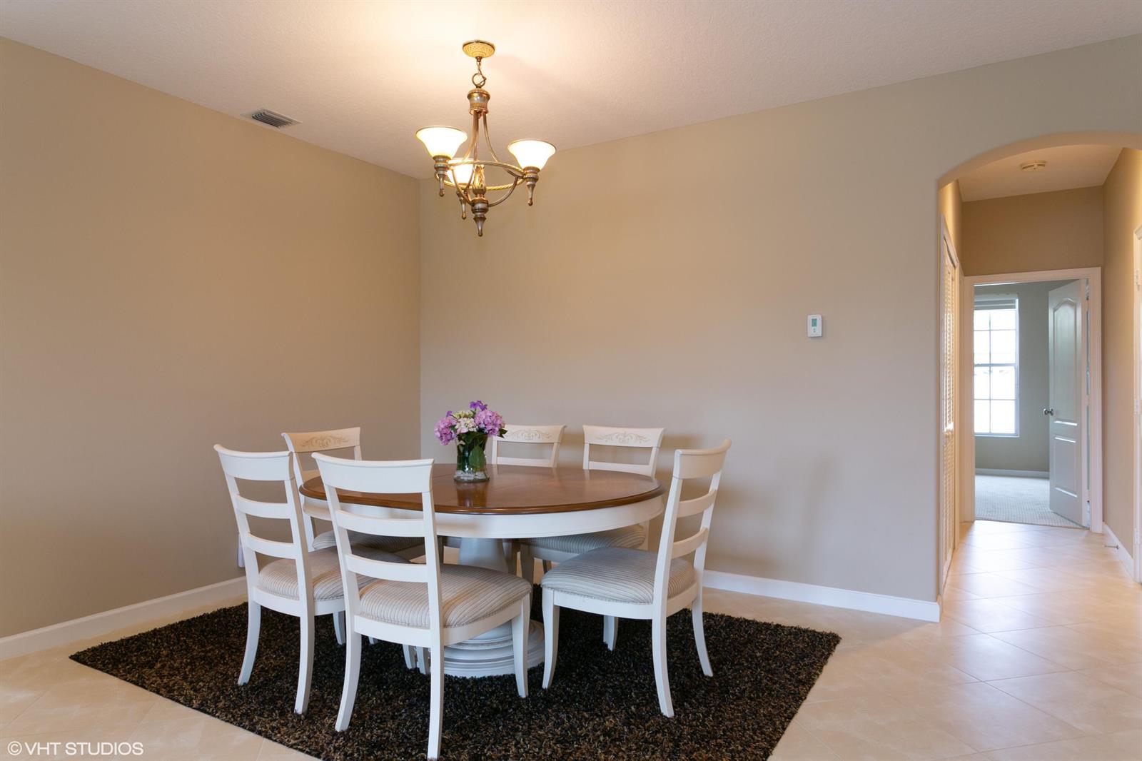 A dining room features a round wooden table, white chairs, and a dark area rug — 8407 Quail Meadow Way, West Palm Beach FL 33412, WEST PALM BEACH, FL