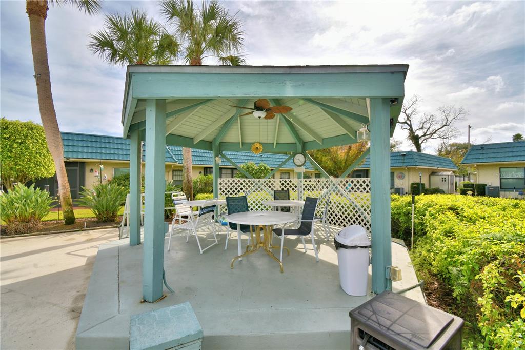 A teal wooden gazebo with patio furniture sits on a concrete slab outdoors — 345 24TH STREET NW UNIT 25, WINTER HAVEN, FL