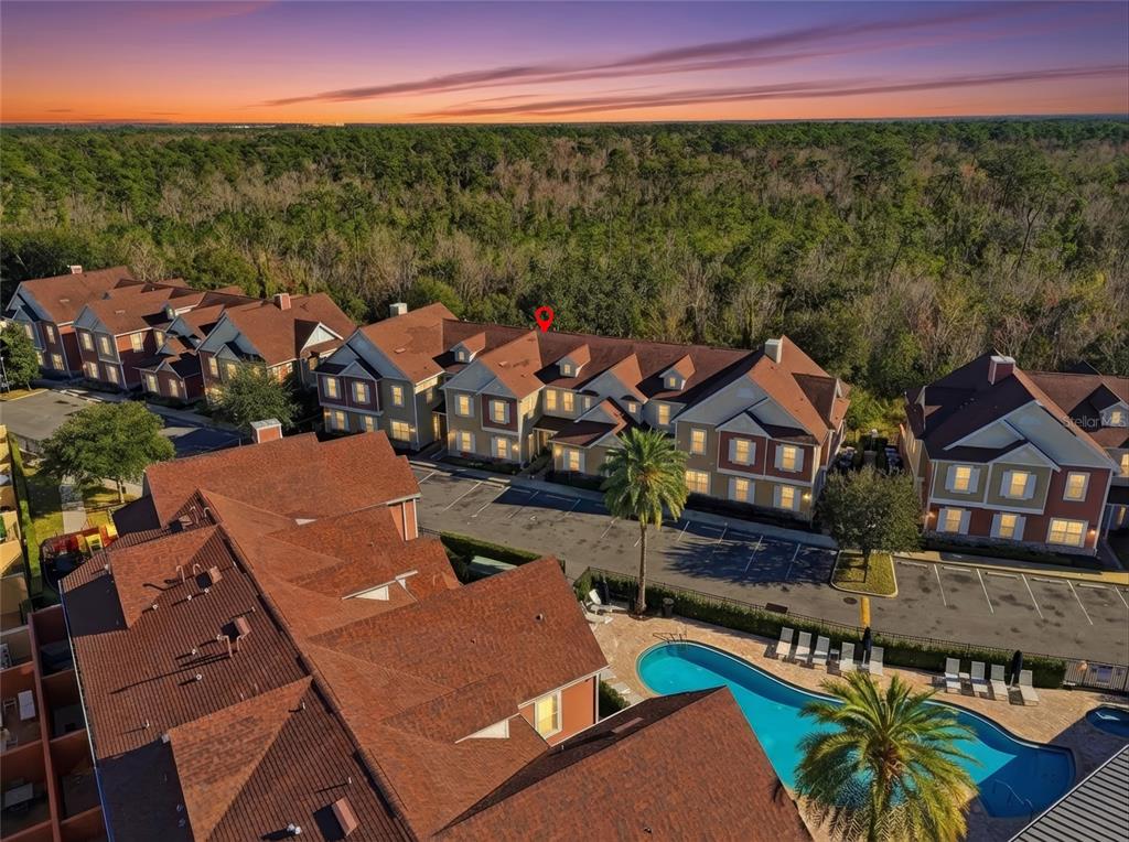 An aerial view shows multi-story apartment buildings with brown roofs, a swimming pool, and trees — 7540 SUNVILLE AVENUE, KISSIMMEE, FL