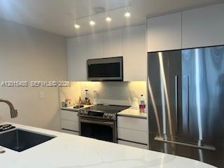 A modern kitchen features white cabinetry, stainless steel appliances, and a white quartz countertop — 401 Ocean Dr # 525, Miami Beach FL 33139, MIAMI BEACH, FL