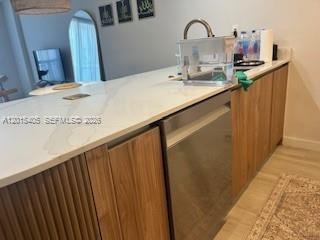 A kitchen island features a white countertop, wood-paneled cabinetry, and a stainless steel dishwasher — 401 Ocean Dr # 525, Miami Beach FL 33139, MIAMI BEACH, FL