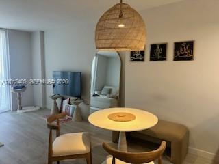 A dining area features a round table, wooden chairs, a bench, and a woven pendant light — 401 Ocean Dr # 525, Miami Beach FL 33139, MIAMI BEACH, FL
