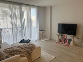 A living room features light wood flooring, a large window with sheer curtains, and a television — 401 Ocean Dr # 525, Miami Beach FL 33139, MIAMI BEACH, FL