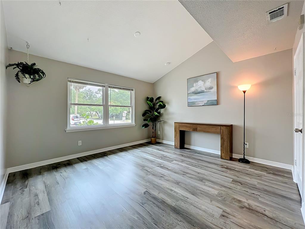A living room features light gray walls, wood-look flooring, a vaulted ceiling, and a console table — 2312 S PARK AVENUE, SANFORD, FL