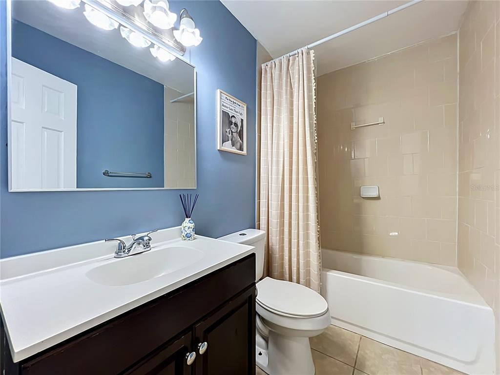 A bathroom features a dark wood vanity, blue walls, a toilet, and a tiled tub — 2312 S PARK AVENUE, SANFORD, FL