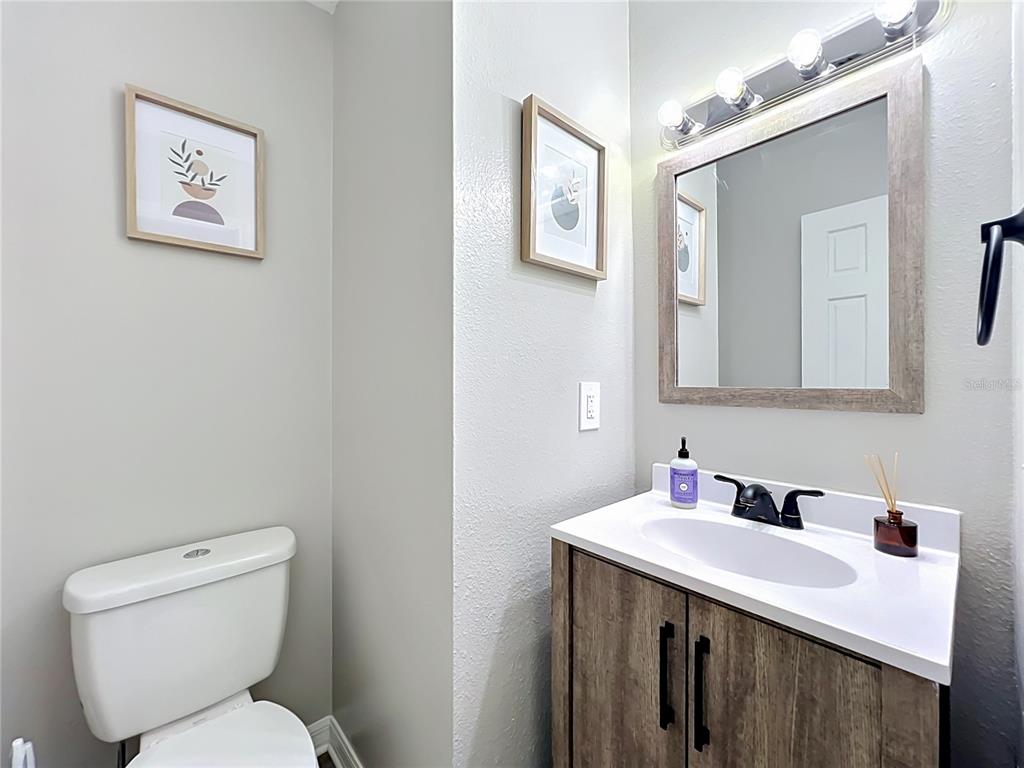 A bathroom features a wood-look vanity, a white sink, a mirror, and a toilet — 2312 S PARK AVENUE, SANFORD, FL