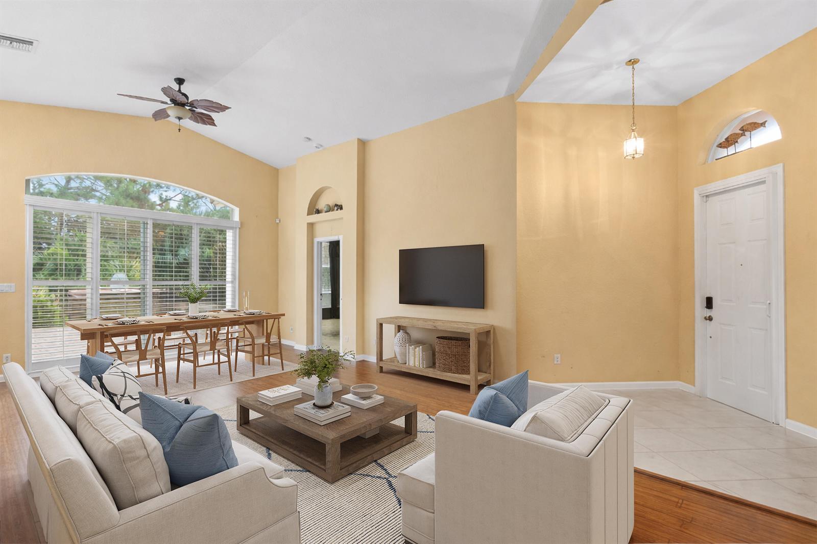 A living room with yellow walls, a dining area, and a television mounted above furniture — 6159 Arlington Way, Fort Pierce FL 34951, FORT PIERCE, FL