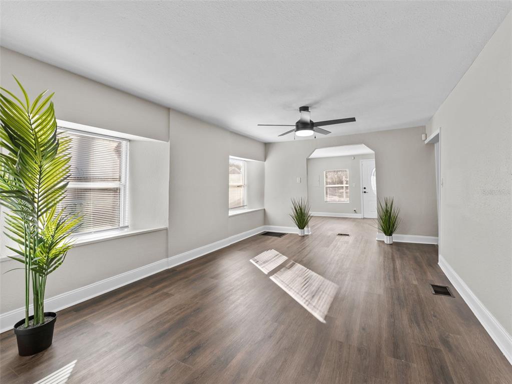 A kitchen features white cabinets, granite countertops, a portable island, and dark wood-look flooring — 3622 E MOHAWK AVENUE, TAMPA, FL