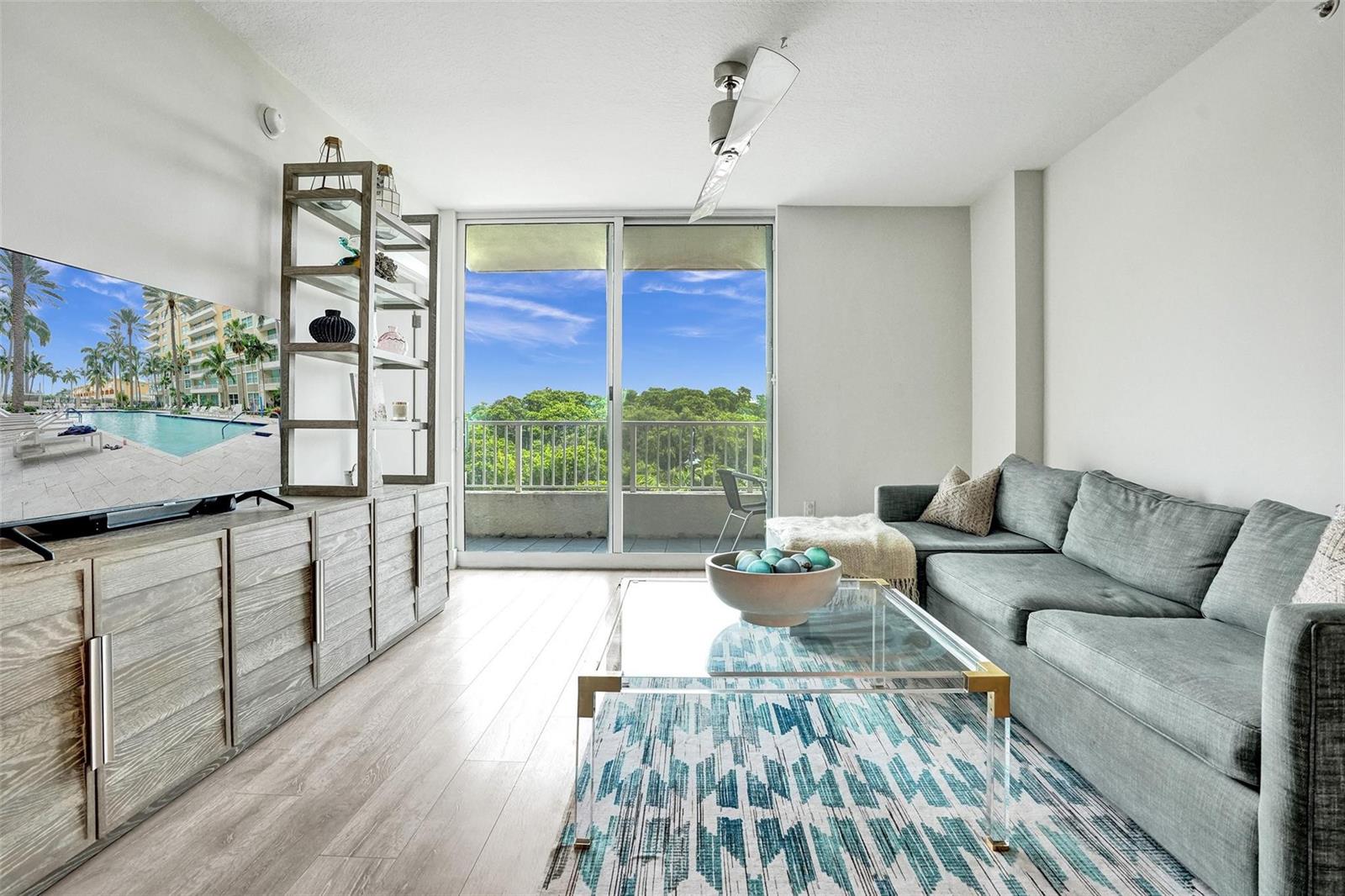 A living room features a grey sectional sofa, glass coffee table, and a balcony view — 700 E Boynton Beach Boulevard # 406, Boynton Beach FL 33435, BOYNTON BEACH, FL