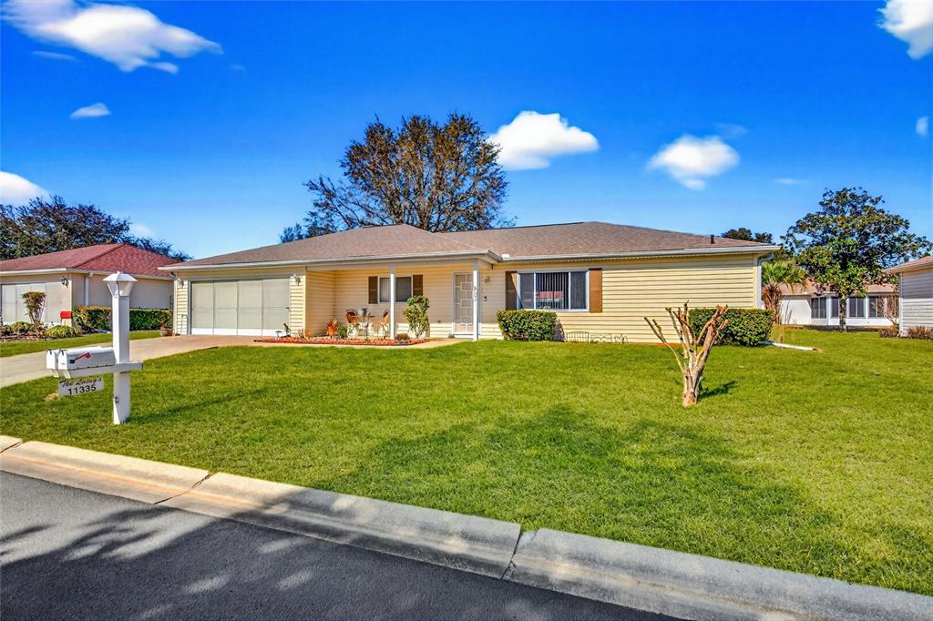 A single-story house with light yellow siding, a two-car garage, and a front lawn — 11335 SW 138TH LANE, DUNNELLON, FL
