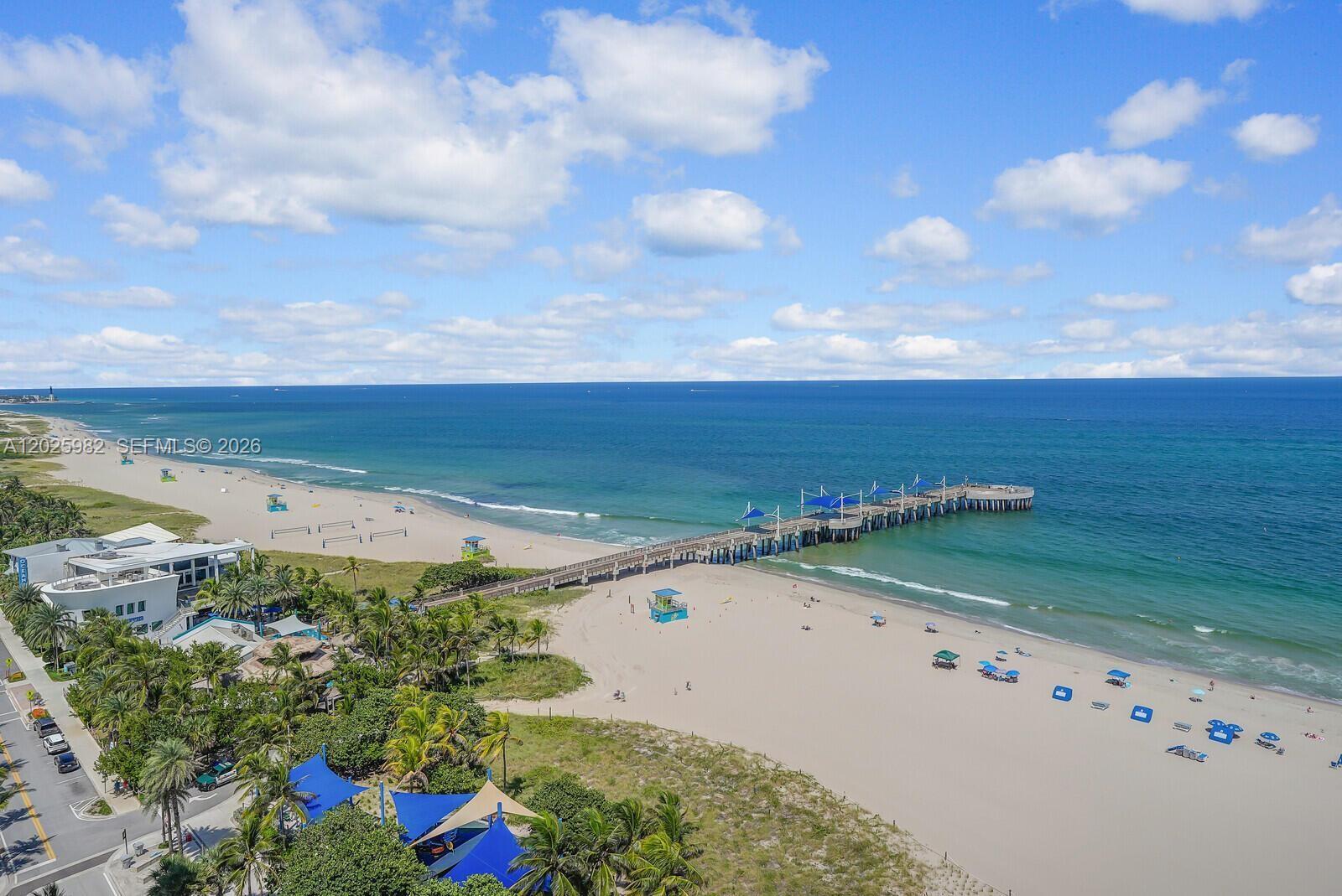 An aerial view shows a long pier extending into the ocean from a sandy beach — 111 N Pompano Beach Blvd # 909, Pompano Beach FL 33062, POMPANO BEACH, FL