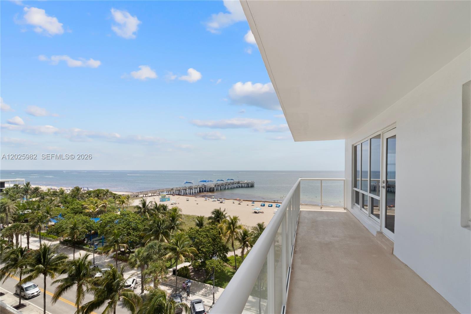A balcony overlooks a sandy beach, palm trees, a pier, and the ocean — 111 N Pompano Beach Blvd # 909, Pompano Beach FL 33062, POMPANO BEACH, FL