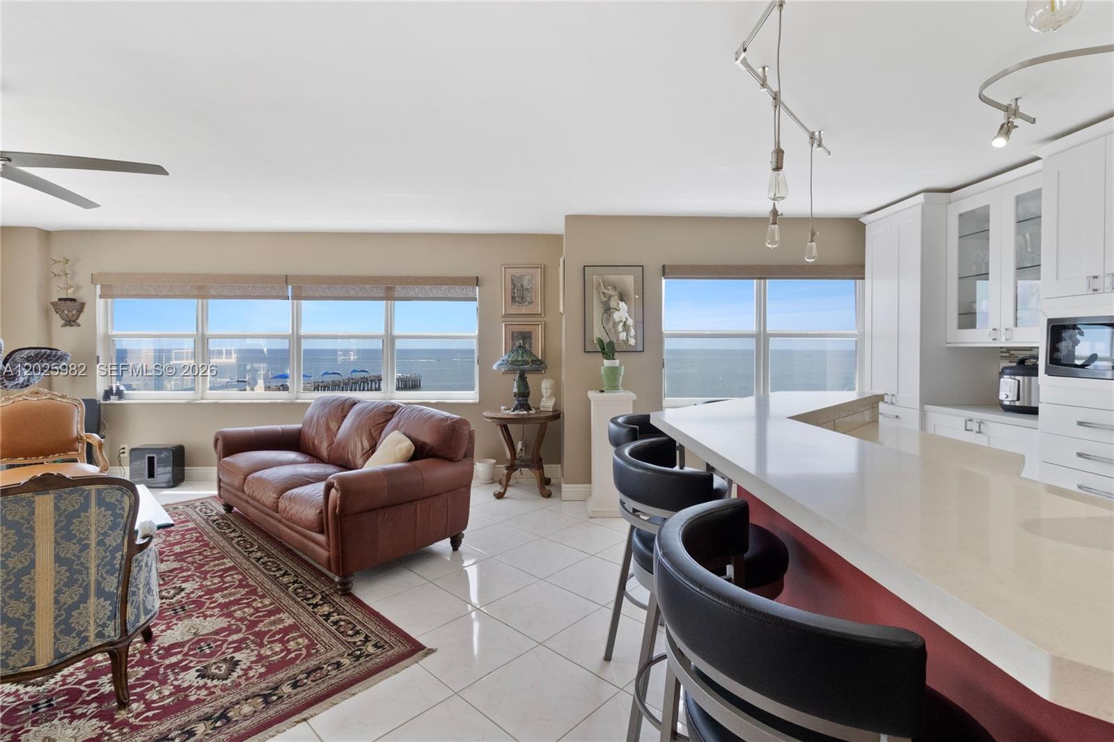 An open-concept living area features a kitchen island, leather sofa, and ocean views — 111 N Pompano Beach Blvd # 909, Pompano Beach FL 33062, POMPANO BEACH, FL